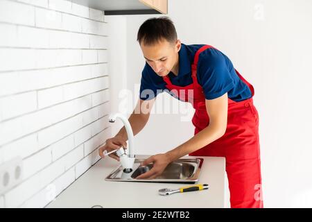partial view of repairman in working overall fixing sink in kitchen Stock Photo