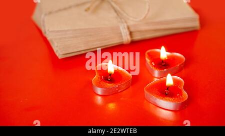 Kraft paper envelopes with red candles on a red background. Valentine day concept Stock Photo