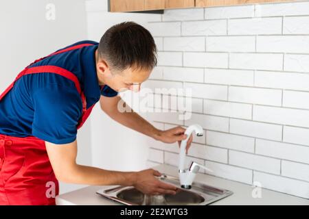 partial view of repairman in working overall fixing sink in kitchen Stock Photo