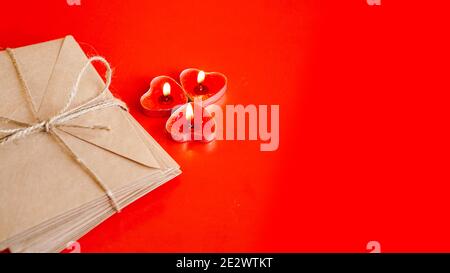 Kraft paper envelopes with red candles on a red background. Valentine day concept Stock Photo