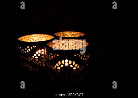 Three ornamental candles burning with black background for copy space Stock Photo