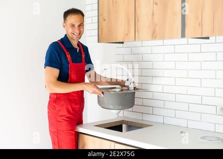 partial view of repairman in working overall fixing sink in kitchen Stock Photo