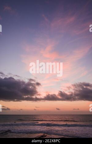 Pink and orange sunset over the Atlantic Ocean with storm clouds overlaying pink clouds in Sao Sebastiao, Ericeira, Portugal. Stock Photo
