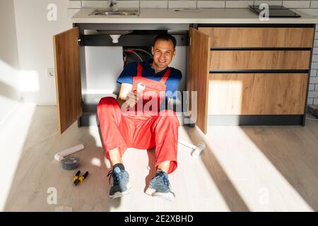 Full length portrait of smiling construction worker in uniform and tool belt isolated on white background Stock Photo