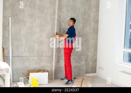 Rear back behind view photo of unrecognizable repairman master using rule to measure the required width of drywall and put label mark Stock Photo