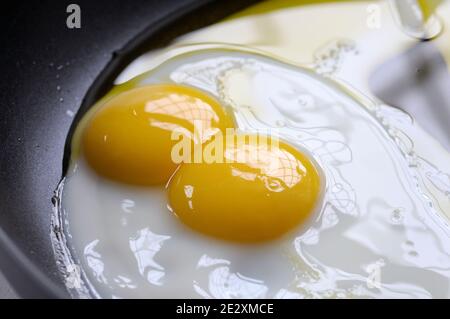 Double yolk fried egg cooking in oil in a frying pan.  Twin yolks are fairly rare and occur roughly one in every 1,000 eggs. Stock Photo
