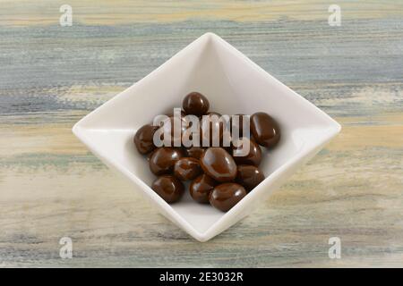 Chocolate covered peanuts candy in white candy dish on table Stock Photo