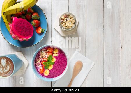 A fresh smoothie bowl made from banana, dragon fruit, milk and strawberries served in a bowl for a healthy nutritious breakfast - Tabletop food and li Stock Photo