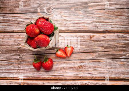 Fresh strawberries in burlap sack on wooden table. vegan food. Top view with copy space. healthy food concept Stock Photo
