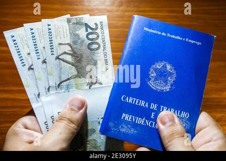 Sorocaba, Brazil. 15th Jan, 2021. Hand holding three 200 reais bills and business card. With the end of the emergency aid of 600 reais in January 2021, about 48 million Brazilians were impacted. Approximately R $ 275 billion was paid in 2020 to 68 million people. Credit: Cadu Rolim/FotoArena/Alamy Live News Stock Photo