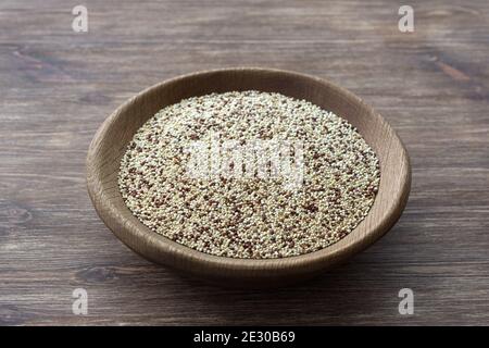 Mixed raw quinoa in wooden bowl on wooden table. Healthy, gluten free superfood Stock Photo