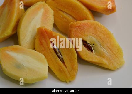 Sliced Chiku or Sepadilla (Manilkara zapota) fruits, or berries, with skin removed, ready to be served (on white background) Stock Photo