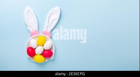 Creative Easter composition. Easter eggs and bunny ears on blue background. Copy space - Image Stock Photo