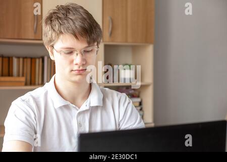 Student in glasses learning at home using laptop. Home school, online education, home education, quarantine concept - Image Stock Photo