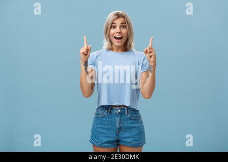 Waist-up shot of impressed enthusiastic creative blonde woman in trendy summer outfit smiling gasping being charmed and thrilled with awesome copy Stock Photo