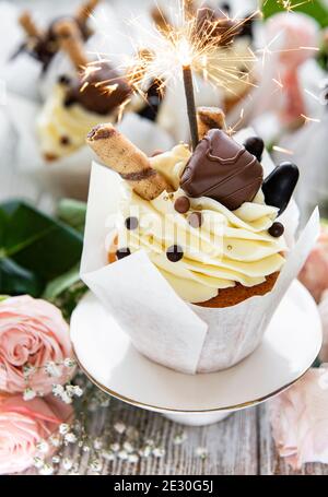 Chocolate cupcakes with burning sparklers on white wooden background Stock Photo