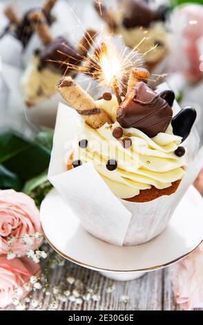 Chocolate cupcakes with burning sparklers on white wooden background Stock Photo