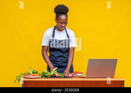 african chef cooking while using her laptop Stock Photo