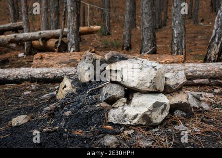 The remains of a fire in the forest. A pile of rocks and ashes from burning trees. Traces of tourists ' rest. Forest fire protection measures. The ban Stock Photo