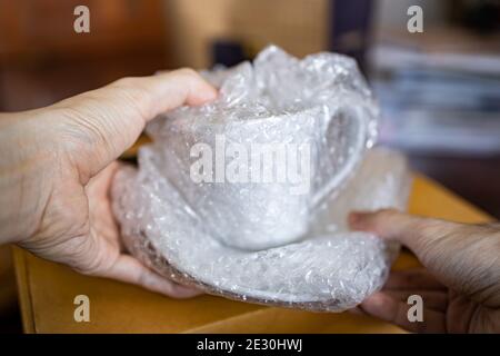 Wrapping a ceramic cup with bubble wrap Stock Photo