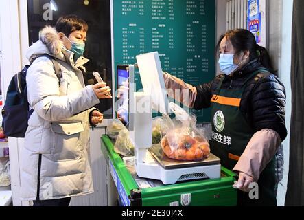 (210116) -- BEIJING, Jan. 16, 2021 (Xinhua) -- A resident pays for goods at a neighborhood supermarket in the Xueyuanlu sub-district of Haidian District, Beijing, capital of China, Jan. 16, 2021. With the Chinese Lunar New Year approaching, Beijing's Xueyuanlu sub-district has adopted multiple methods to ensure vegetable supplies to its residents. (Xinhua/Ren Chao) Stock Photo