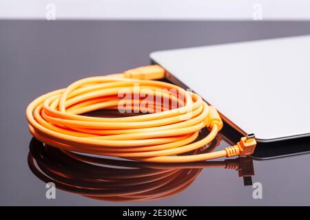 laptop with orange rolled cable. Stock Photo