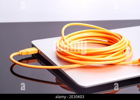 laptop with orange rolled cable. Stock Photo