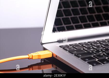 laptop with orange rolled cable. Stock Photo