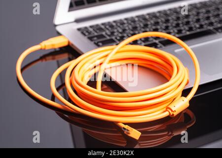 laptop with orange rolled cable. Stock Photo