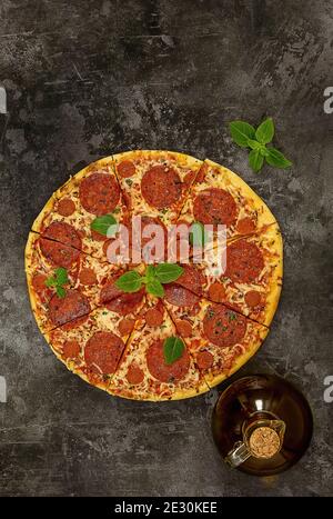Tasty pepperoni pizza and fresh basil on dark background. Stock Photo