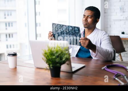 Side view of African American man doctor wearing surgeon medic suit studying chest X-Ray image. Stock Photo