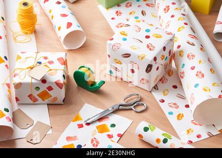 Collection of various tools and patterned paper placed on desk near wrapped gift boxes before holiday celebration Stock Photo