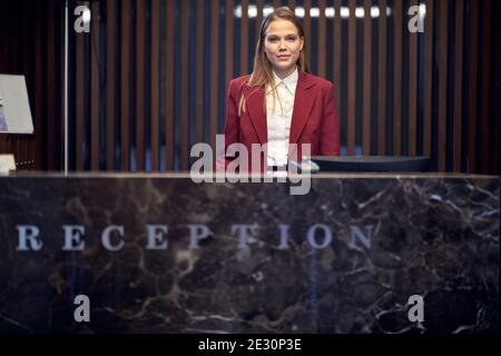 A pretty female receptionist behind the counter at the hotel waiting for the guests. Tourism, business, hotel Stock Photo