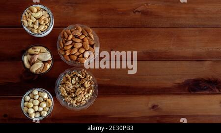 Mixed nuts in different bowls on wooden table. Top view with place for text Stock Photo