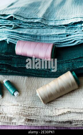 Cuts of muslin in green efcalipt beige and spools of thread in the same color. Matching fabrics and threads. Textile backgrounds. Stock Photo
