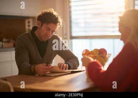 A young couple spending a sunny morning in a relaxed atmosphere at the kitchen together. Reading, relationship, love Stock Photo