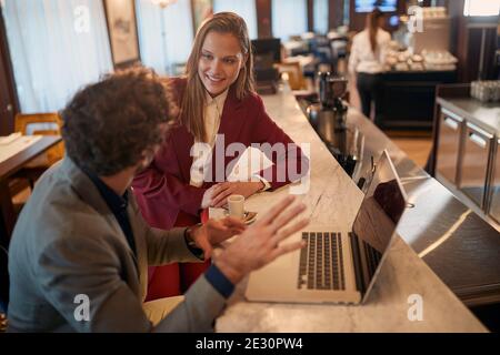 A young businessman in a relaxed atmosphere at a coffee break at the bar explaining new business deal to his female colleague. Business, people, bar Stock Photo