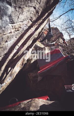 A female climber cuts loose bouldering on granite in Brione, Switzerland Stock Photo