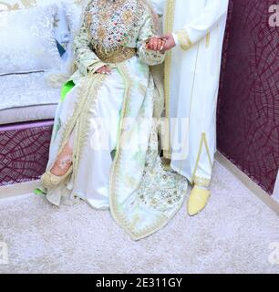 Moroccan Wedding. The groom is wearing Moroccan jellaba. He holds in the hands of the bride who wears the MOROCCAN caftan Stock Photo