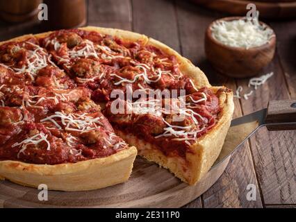 Slice of deep dish sausage pizza on a wooden platter Stock Photo