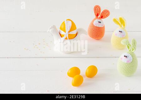 Arrangement decoration Happy Easter holiday background concept. Easter painted eggs with handmade knitted eggs on white wooden table. Pastel colors Stock Photo