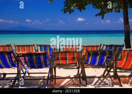View on isolated colorful empty deck chairs in a row on tropical beach, Thailand, Ko Phi Phi - tourism industry perspective concept Stock Photo