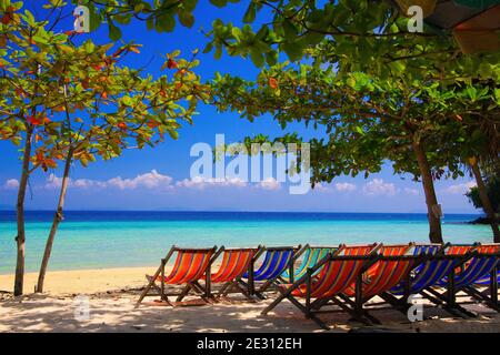 View on isolated colorful empty deck chairs in a row on tropical beach, Thailand, Ko Phi Phi - tourism industry perspective concept Stock Photo