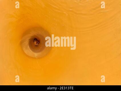 Draining rusty or dirty water from the bath to the sewer, close up. Stock Photo