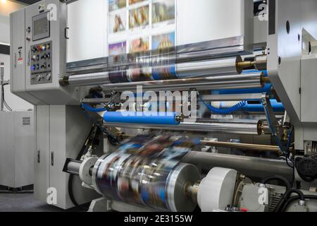 Large offset printing press or magazine running a long roll off paper in production line of industrial printer machine. Stock Photo