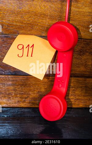 Writing 911 on memo post reminder.  sticky paper with text 911 and landline phone. Stock Photo