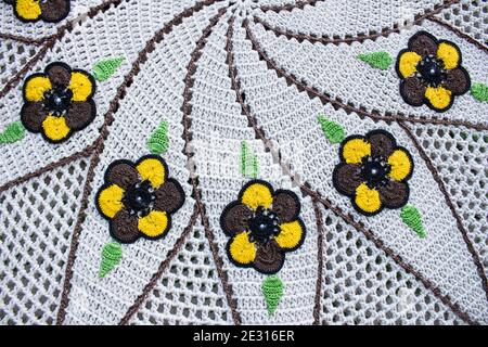 White and brown crochet piece with yellow and brow flower with two green leaves next each one Stock Photo