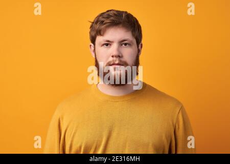 Troubled displeased bearded man frowns face, feels sad, distressed and upset, being bored sitting on quarantine, unhappy to miss good chance, dressed Stock Photo