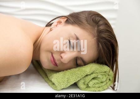 Young woman resting in massage parlor, put her head on a towel. Stock Photo