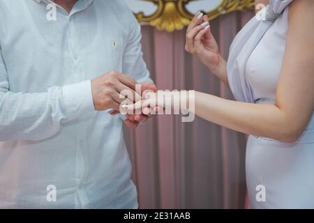A man is giving a ring to his girlfriend and wearing in on her finger. Young woman caught because her boyfriend gives an henna ring at breakfast . He Stock Photo